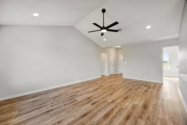 a view of empty room with wooden floor and ceiling fan