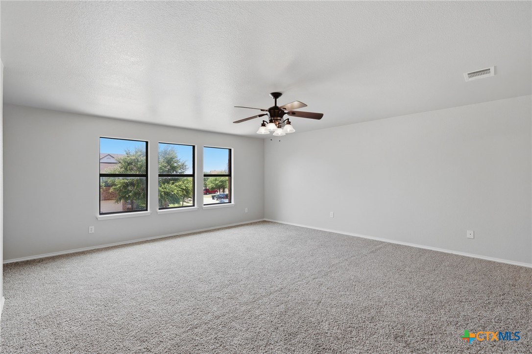 8716 Starview Street Temple, TX 76502 - Photo 12 of 36 Comfortable primary bedroom featuring neutral carpeting, a ceiling fan, and bright natural lighting.