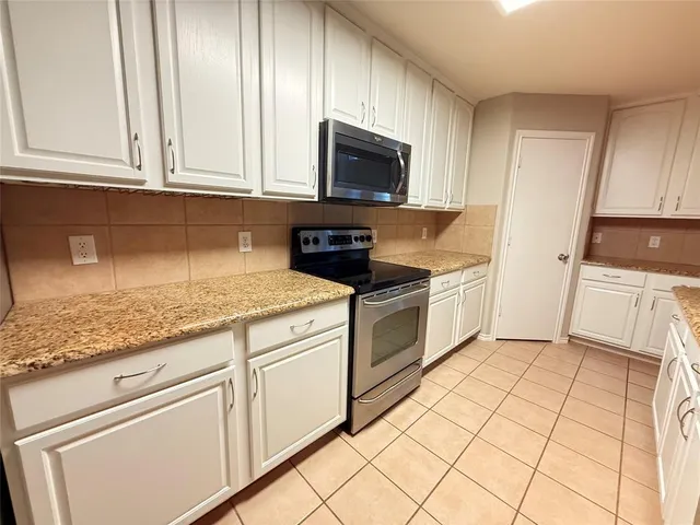 a kitchen with granite countertop white cabinets stainless steel appliances and sink