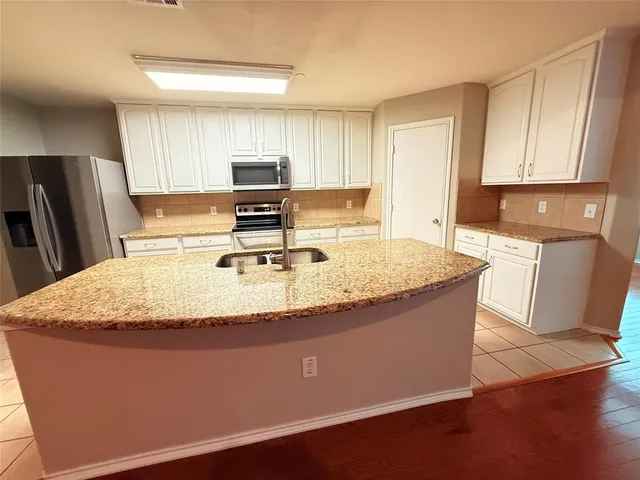 a kitchen with granite countertop a sink a stove and a refrigerator