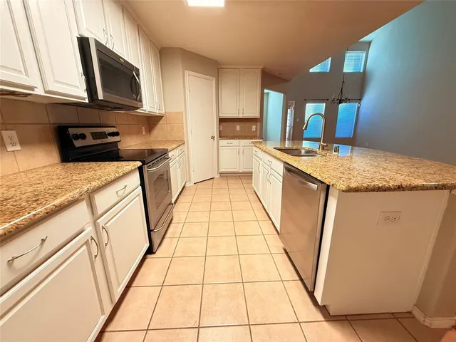 a kitchen with stainless steel appliances granite countertop a stove a sink and a microwave