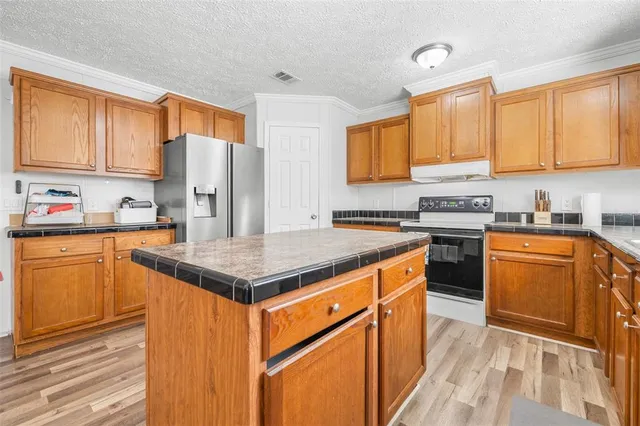 a kitchen with stainless steel appliances granite countertop a stove a sink dishwasher and a refrigerator