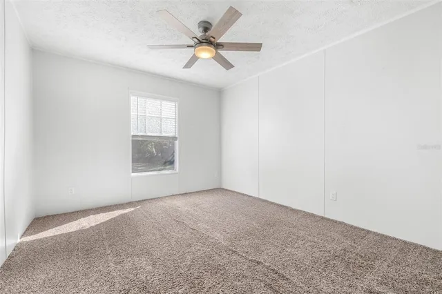 an empty room with a window and a fan