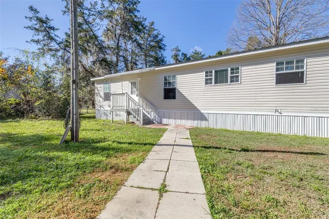 a backyard of a house with plants and large tree