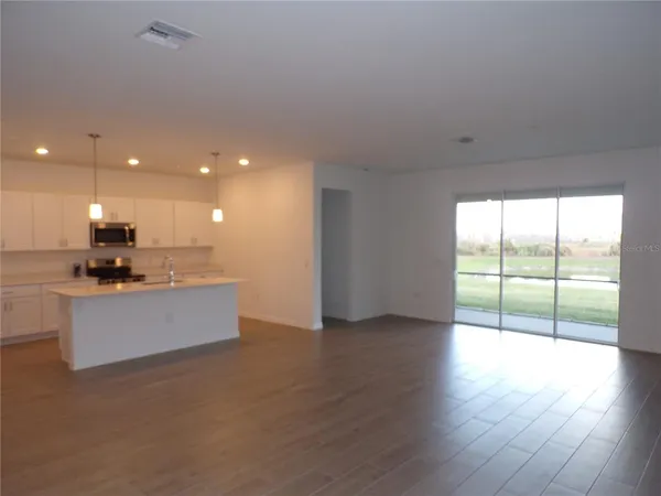 a open kitchen with kitchen island a sink wooden floor and a large window