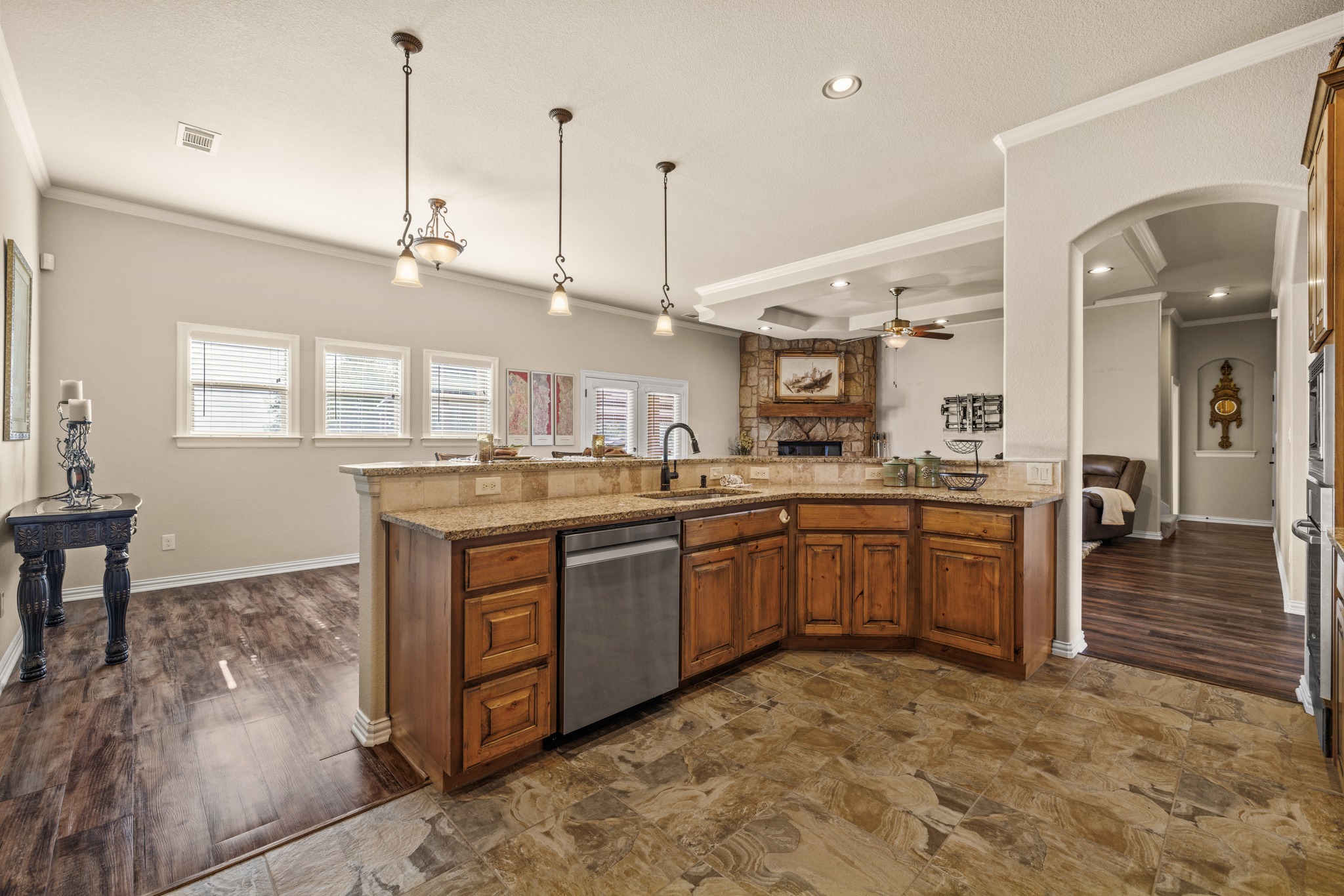 204 Skyline Road Georgetown, TX 78628 - Photo 40 of 40 Kitchen featuring wood finish cabinetry, crown molding, open floor plan, pendant lighting, and light stone countertops