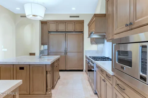 a kitchen with kitchen island granite countertop a stove a sink and a refrigerator