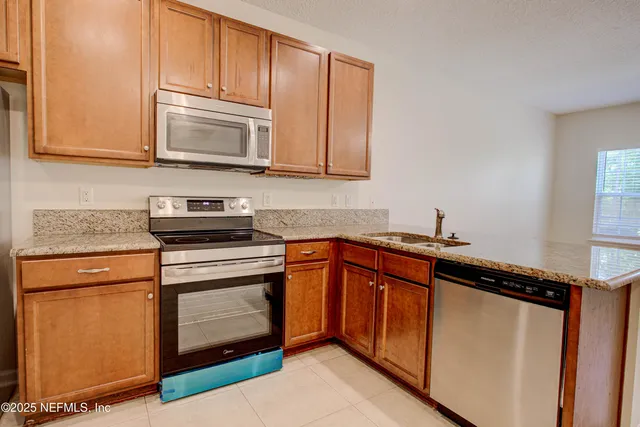 a kitchen with stainless steel appliances granite countertop a sink stove and microwave