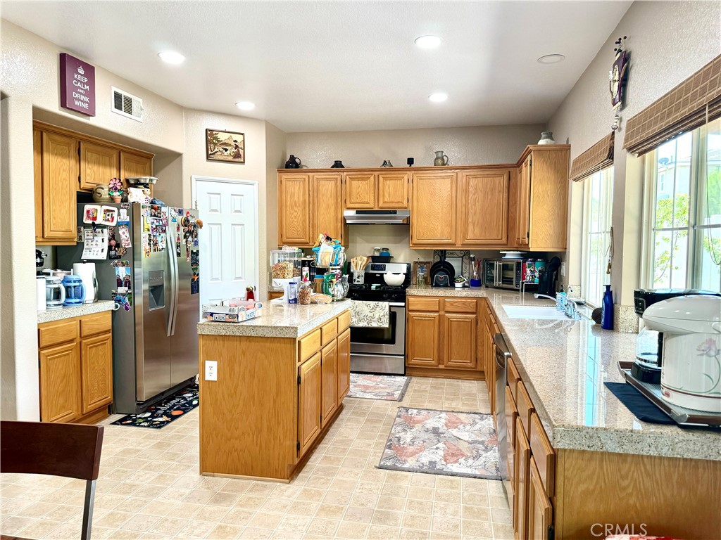 37041 Populus Avenue Palmdale, CA 93552 - Photo 9 of 30 a large kitchen with stainless steel appliances granite countertop a stove top oven a sink dishwasher and cabinets with wooden floor