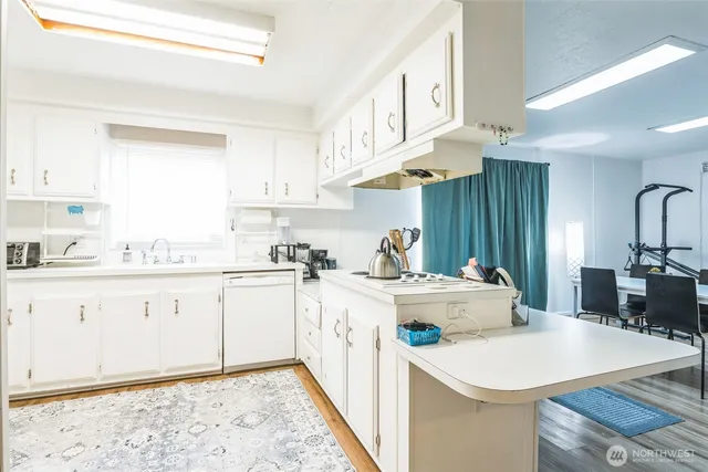 a kitchen with stainless steel appliances granite countertop a sink a stove a refrigerator and white cabinets