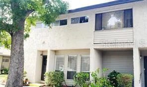 a view of a white house next to a large tree