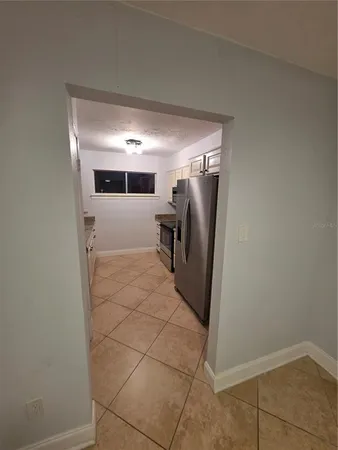 a view of a refrigerator in kitchen and an empty room