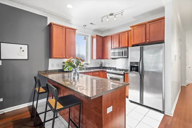 a kitchen with stainless steel appliances granite countertop a refrigerator a sink and a stove with wooden floors