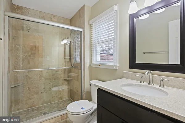 a bathroom with a shower sink vanity mirror and toilet