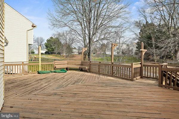 a view of a deck with large trees and wooden fence