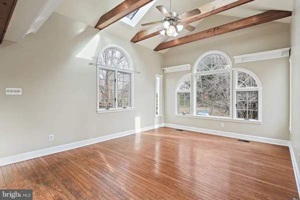 a view of a livingroom with wooden floor a ceiling fan and windows
