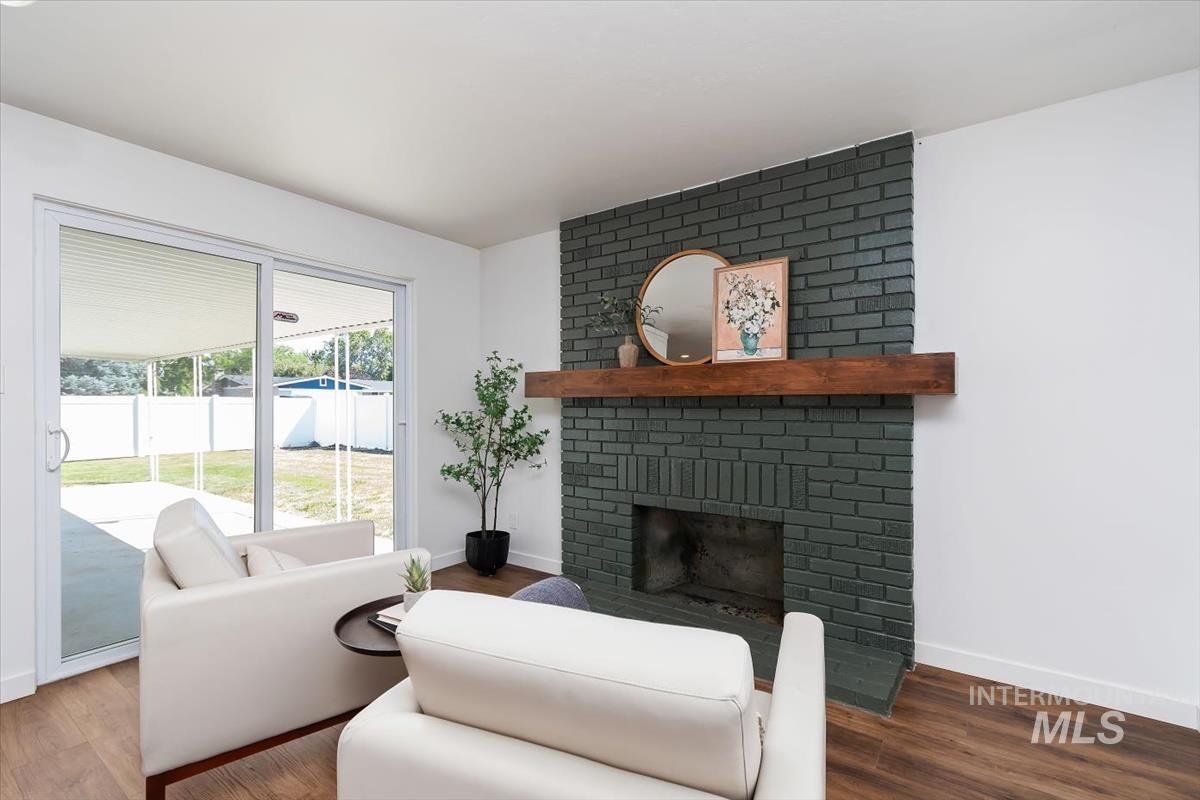 2217 North Middlefield Road Boise, ID 83704 - Photo 21 of 34 Living area featuring a painted brick fireplace with a wood mantel, wood-finish flooring, and white walls