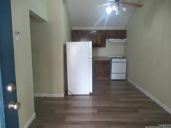 a view of kitchen and empty room with wooden floor