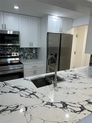 a kitchen with stainless steel appliances kitchen island granite countertop a refrigerator and a stove top oven