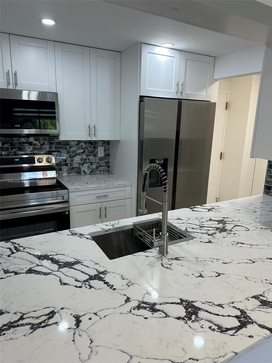 5280 Northwest 7th Street, Unit 306 Miami, FL 33126 - Photo 1 of 23 a kitchen with stainless steel appliances kitchen island granite countertop a refrigerator and a stove top oven