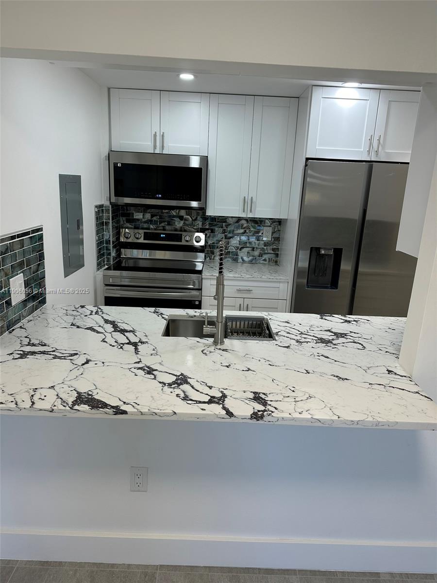 5280 Northwest 7th Street, Unit 306 Miami, FL 33126 - Photo 2 of 23 a kitchen with stainless steel appliances kitchen island granite countertop a sink and a stove top oven