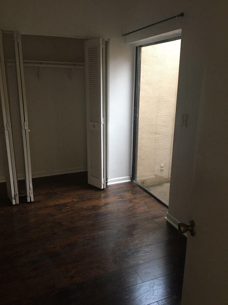 1189 Northwest 13th Street, Unit 7 Boca Raton, FL 33486 - Photo 9 of 15 an empty room with wooden floor and windows with curtains