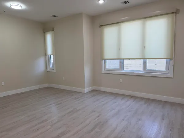 an empty room with wooden floor and windows