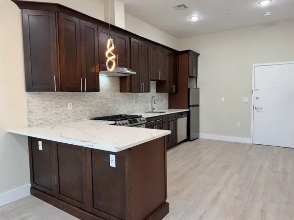 a kitchen with stainless steel appliances granite countertop wooden cabinets a stove and a sink