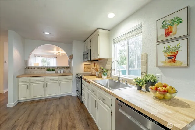 a kitchen with a sink a stove a window cabinets and stainless steel appliances