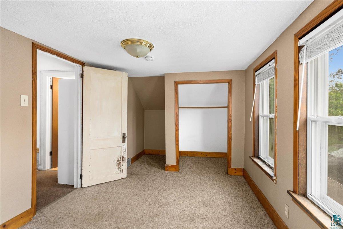 424 East Upham Road Duluth, MN 55811 - Photo 16 of 38 Carpeted room with multiple windows, an open doorway, and a built-in closet with shelving