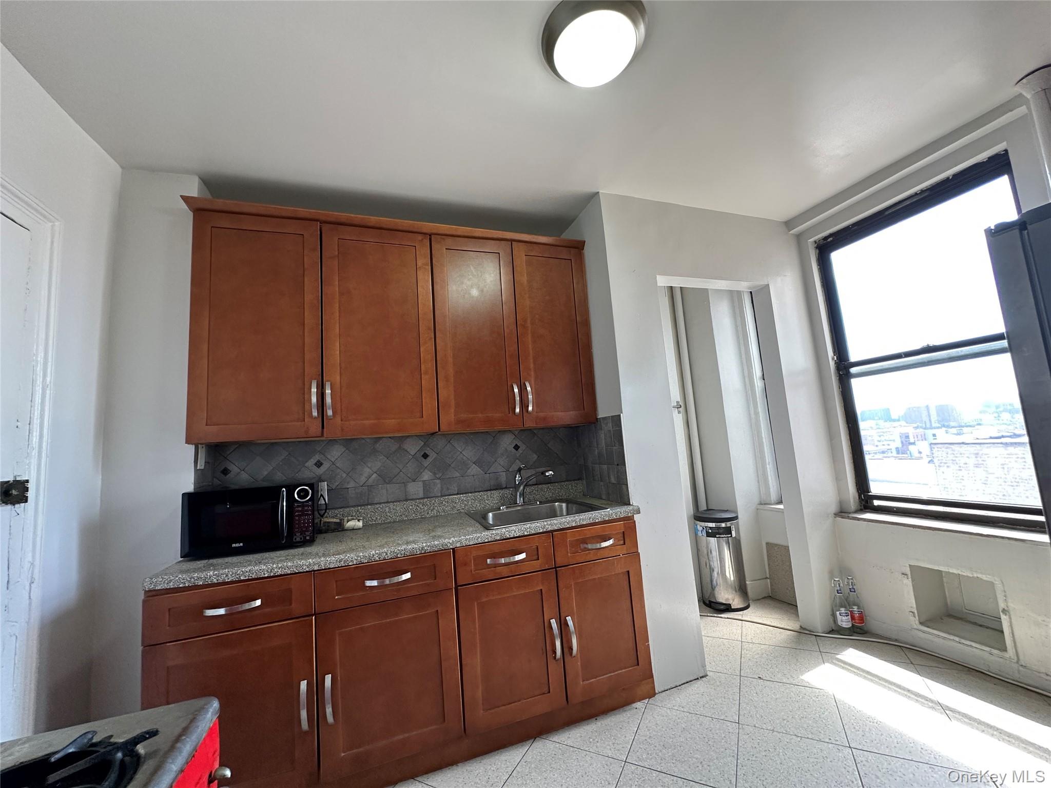 409 Edgecombe Avenue, Unit 7F Manhattan, NY 10032 - Photo 15 of 22 a kitchen with stainless steel appliances granite countertop wooden cabinets a sink and a window