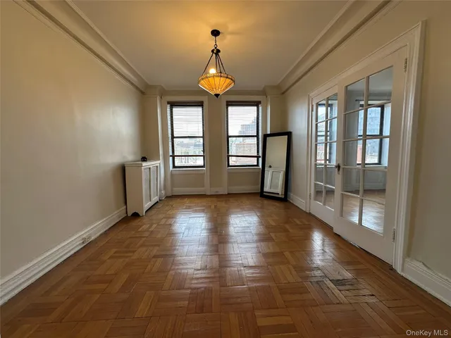 a view of an empty room with window and wooden floor