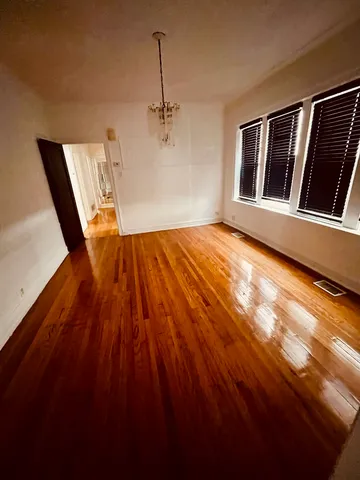 a view of an empty room with wooden floor and windows