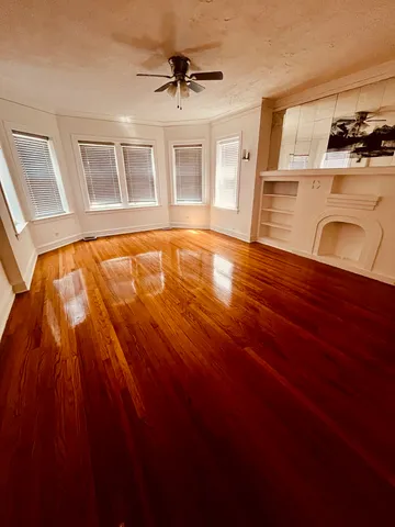a view of an empty room with kitchen natural light and wooden floor
