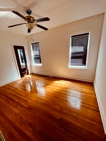 a view of room with hardwood floor and a ceiling fan
