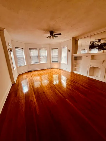 a view of an empty room with window and wooden floor