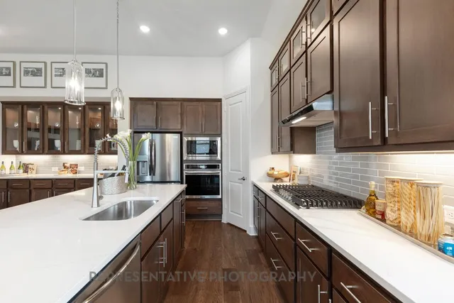 a kitchen with stainless steel appliances granite countertop a sink a stove and a refrigerator