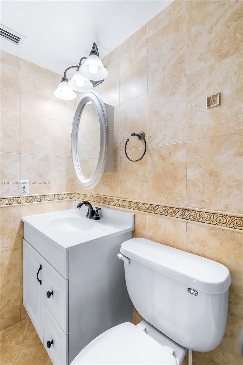2025 Northeast 164th Street, Unit 907 North Miami Beach, FL 33162 - Photo 26 of 33 a bathroom with a toilet a sink and a mirror