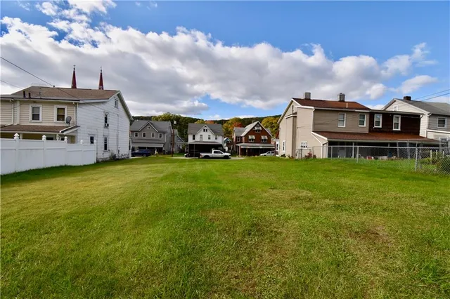 a view of a house with a big yard and large trees