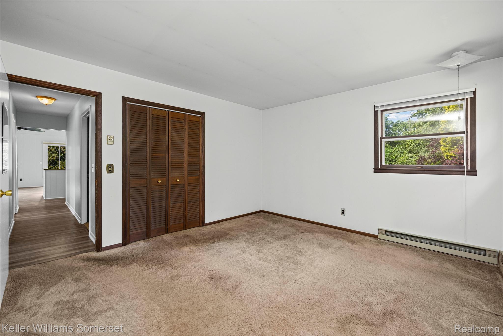 2344 Rochester Road Leonard, MI 48367 - Photo 28 of 66 Carpeted room featuring a window with a green outdoor scene, a louvered bi-fold closet, and baseboard heating