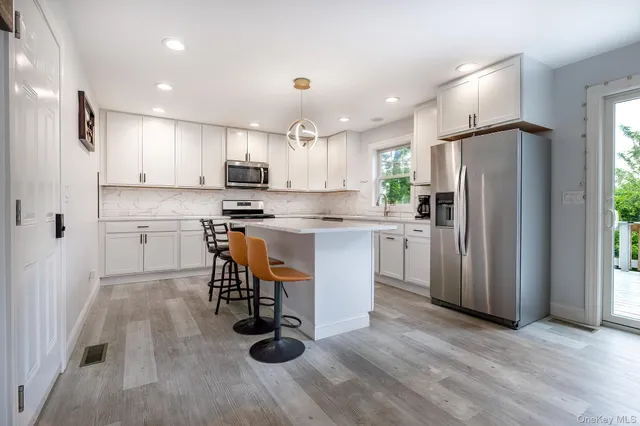 a kitchen with stainless steel appliances granite countertop a refrigerator a stove a sink dishwasher and a refrigerator with wooden floor