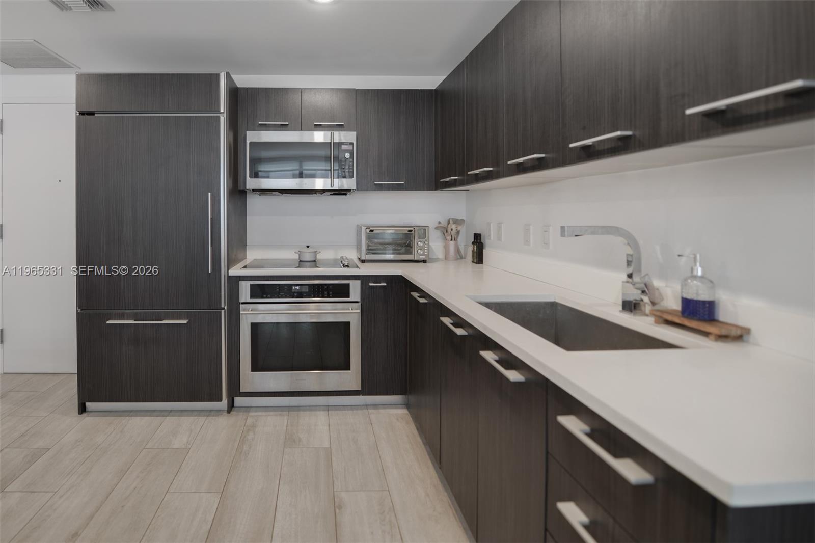 45 Southwest 9th Street, Unit 1107 Miami, FL 33130 - Photo 12 of 50 a kitchen with granite countertop a sink and a stove top oven
