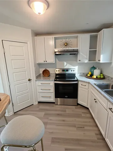 a kitchen with stainless steel appliances a stove a sink cabinets and wooden floor