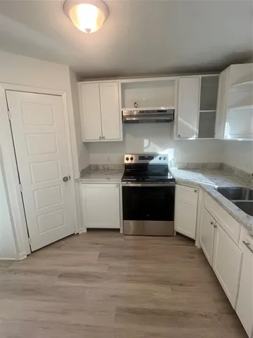 a kitchen with stainless steel appliances granite countertop a stove a sink and white cabinets