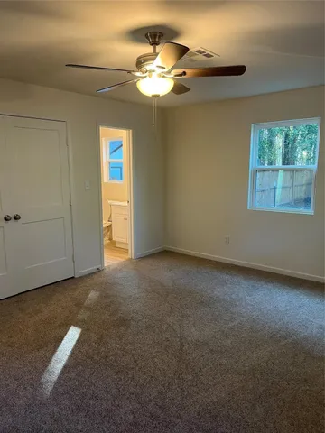 an empty room with a chandelier fan and windows