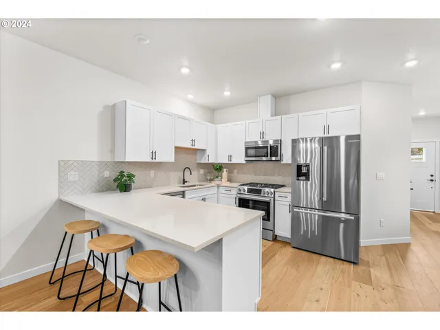 a kitchen with stainless steel appliances a stove a sink a refrigerator and cabinets