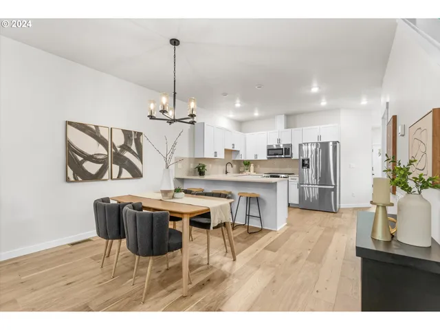 a open kitchen with stainless steel appliances kitchen island granite countertop a dining table chairs and white cabinets