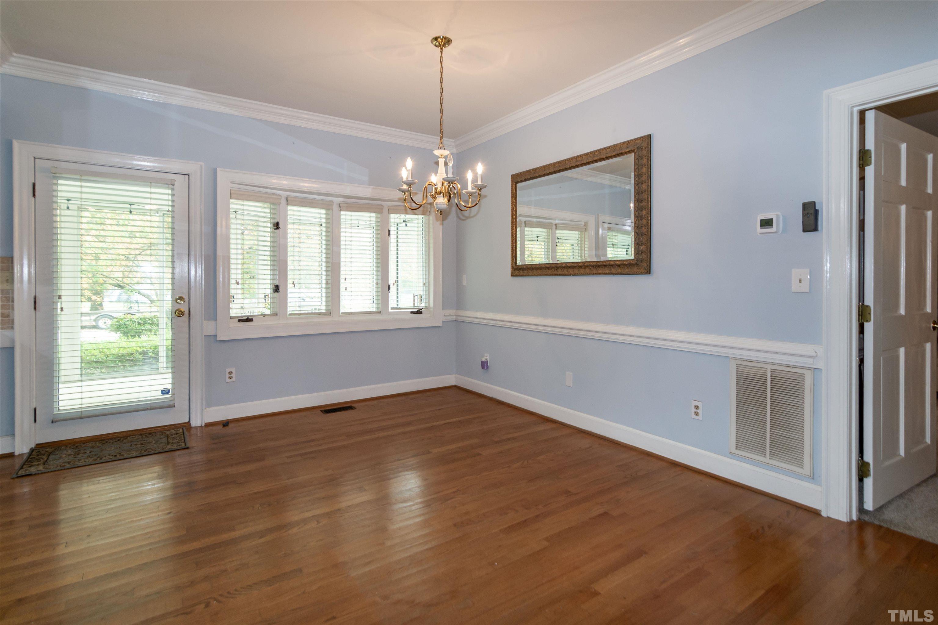 7020 Zebulon Road Wake Forest, NC 27587 - Photo 23 of 45 an empty room with wooden floor chandelier and windows