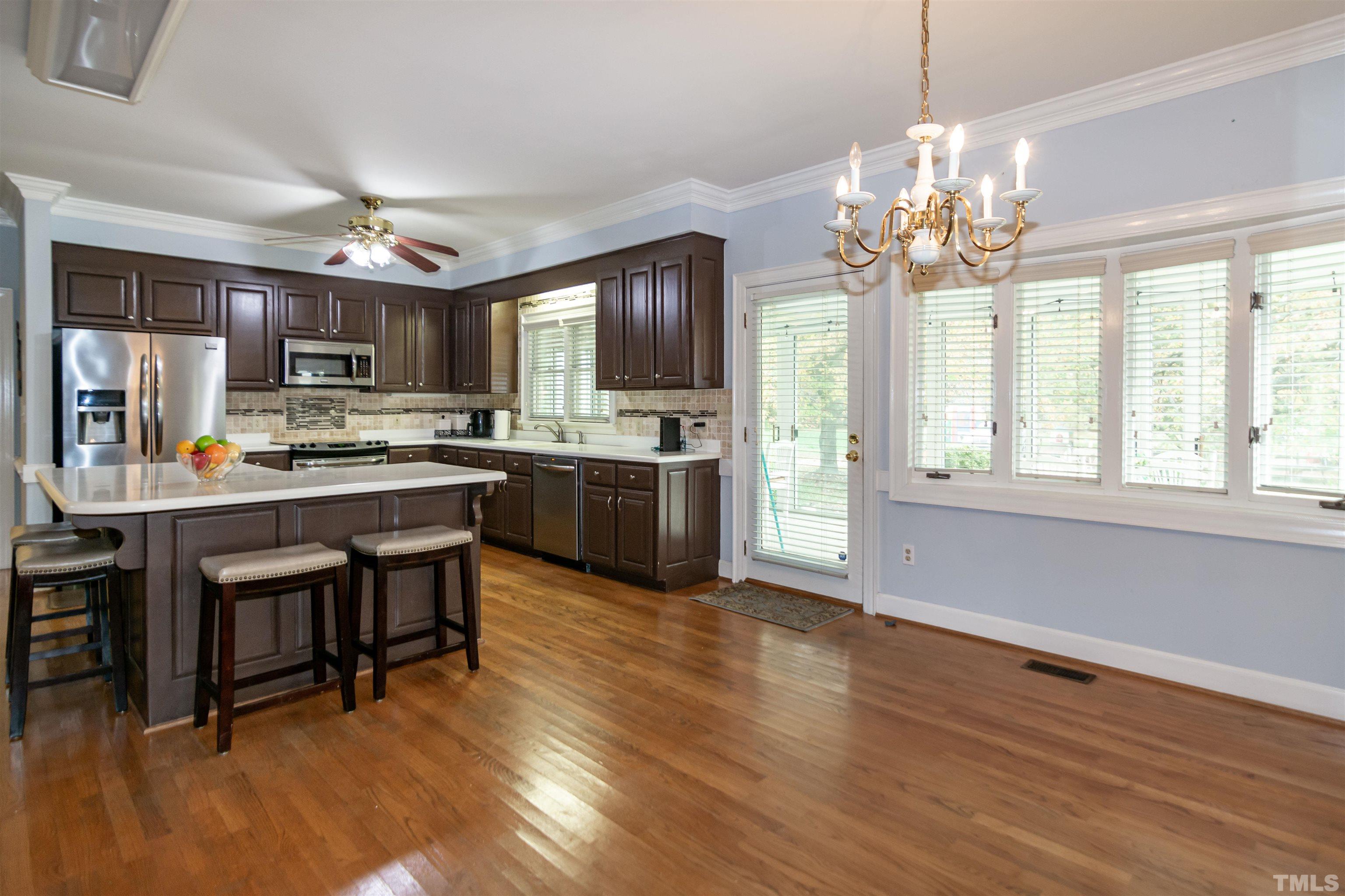 7020 Zebulon Road Wake Forest, NC 27587 - Photo 9 of 45 a kitchen with stainless steel appliances granite countertop a stove top oven a sink dishwasher a dining table and chairs with wooden floor