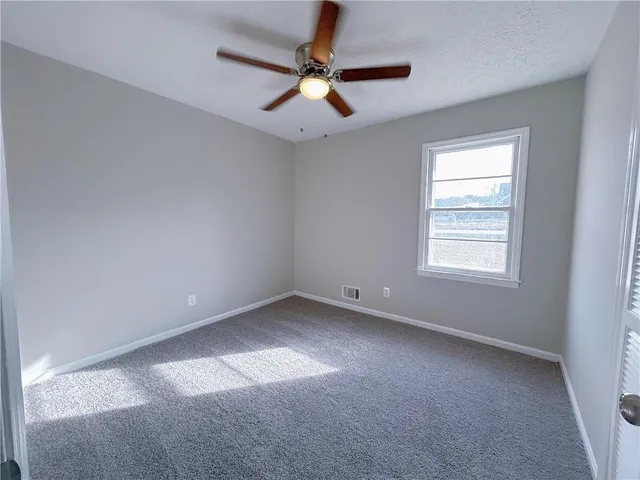 an empty room with a window and a fan